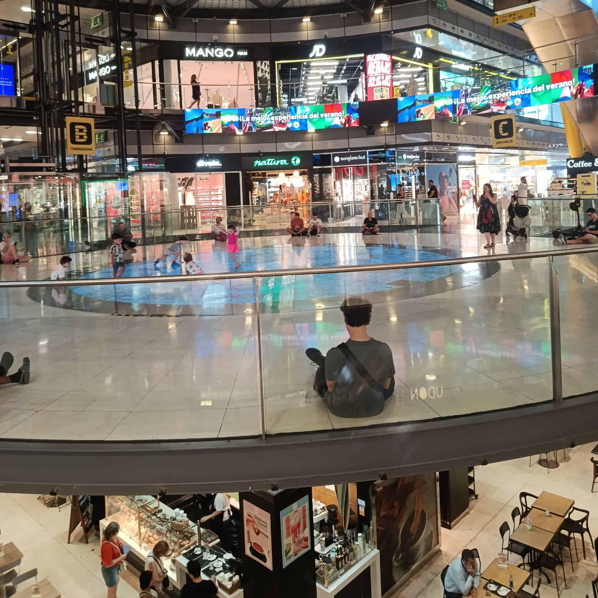 Modern airport terminal with digital displays and travelers waiting.